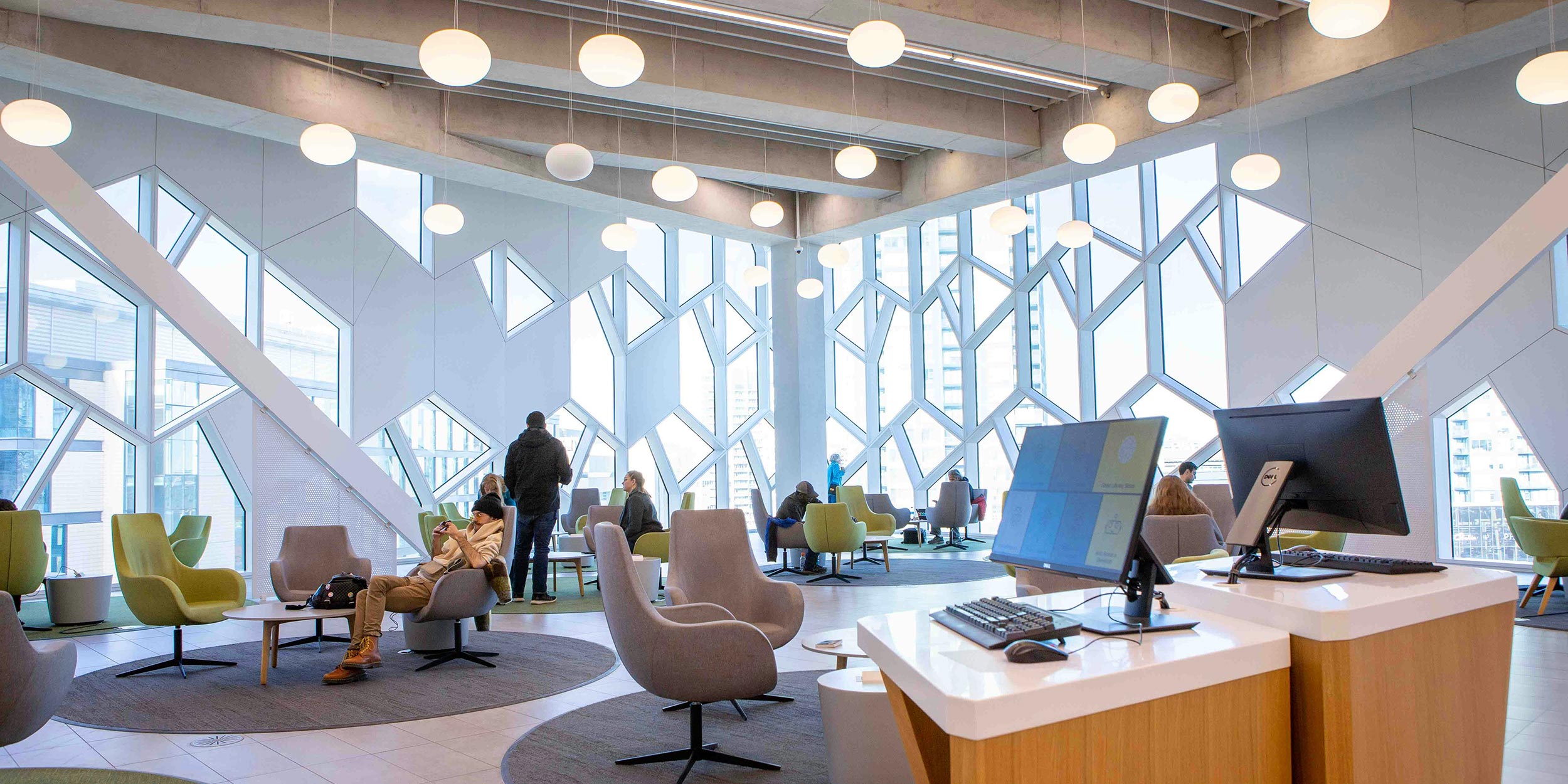 Modern office lounge with geometric windows, round lights, and people working