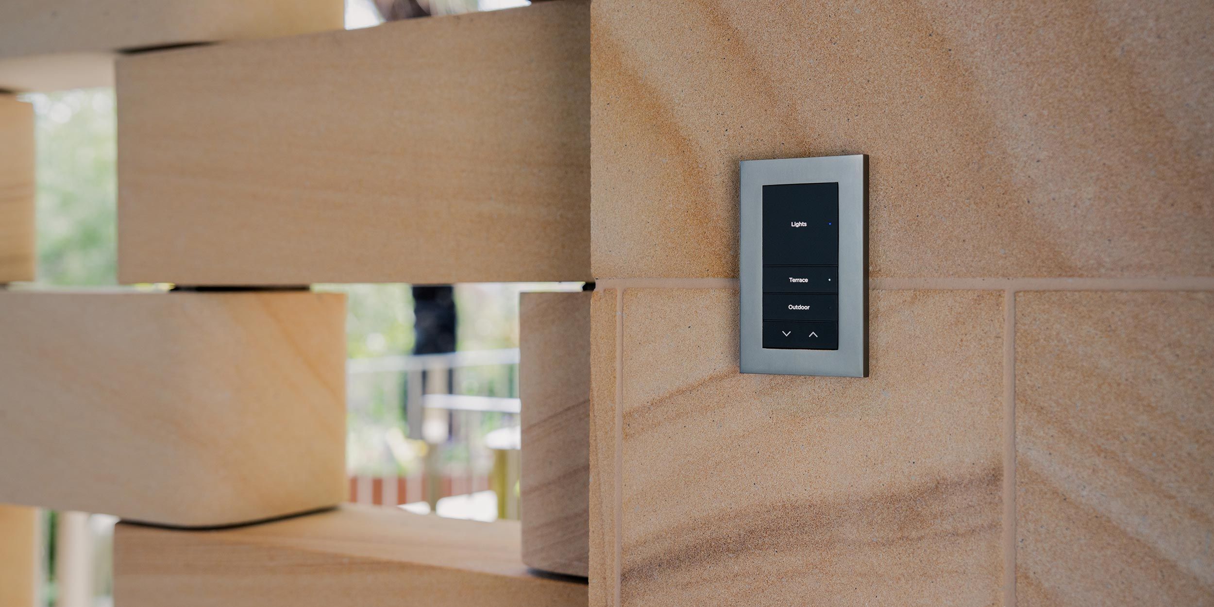 Wall-mounted smart lighting control panel on tan brick wall